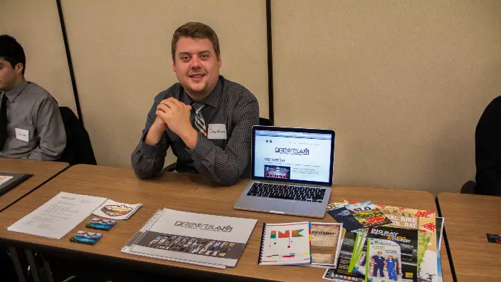 Photograph of a student showcasing their graphic designs.