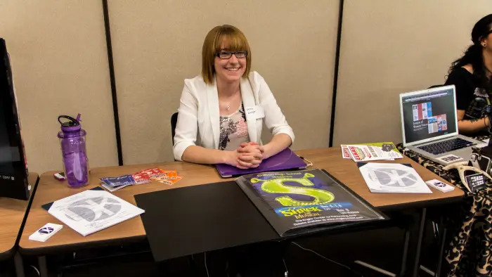 Image of student showcasing their graphic design projects at a table.