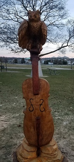 Picture of a carved owl sitting on top of a cello