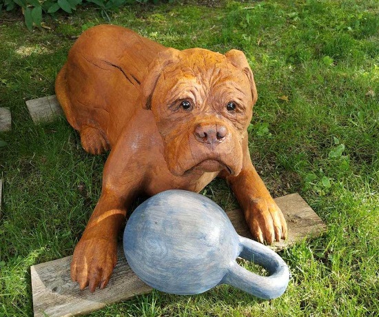 Picture of a carved dog laying down with a toy