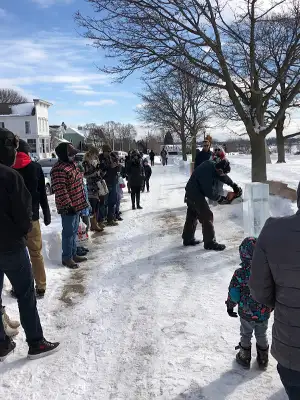 Garret Carving an Ice Block with People Watching
