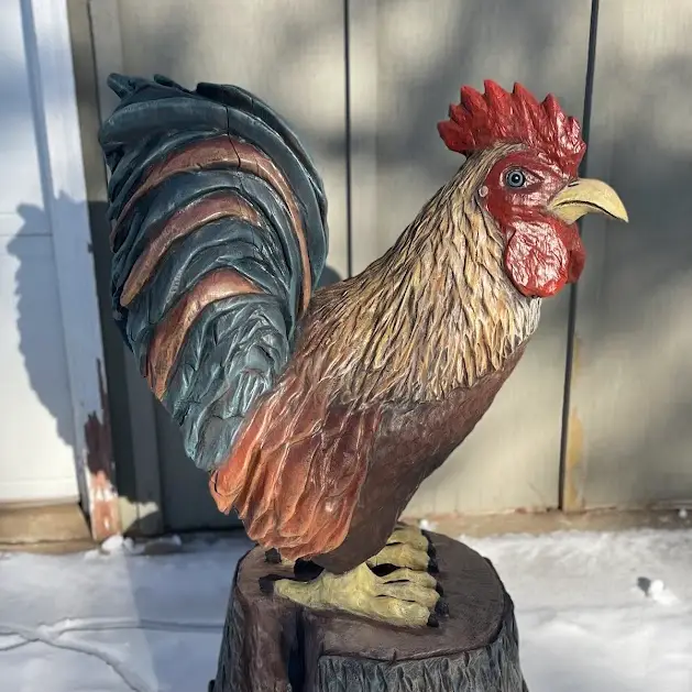 Large, stained, and painted chicken chainsaw carving.